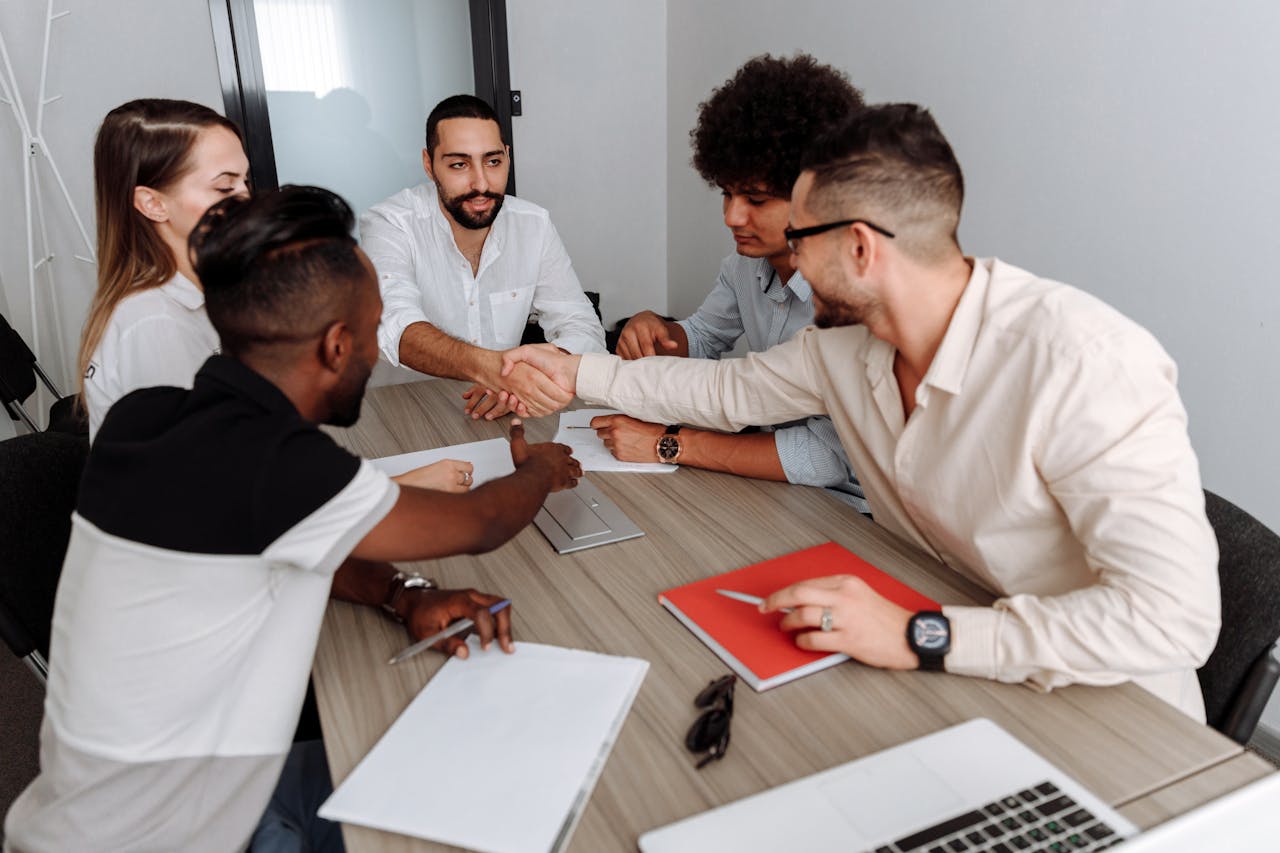 A diverse group of professionals collaborating in a modern office setting, shaking hands to signify teamwork.