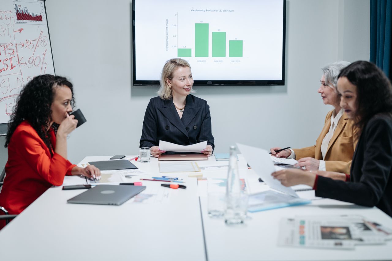 Businesswomen engaged in a productive meeting in a modern conference room with charts displayed.